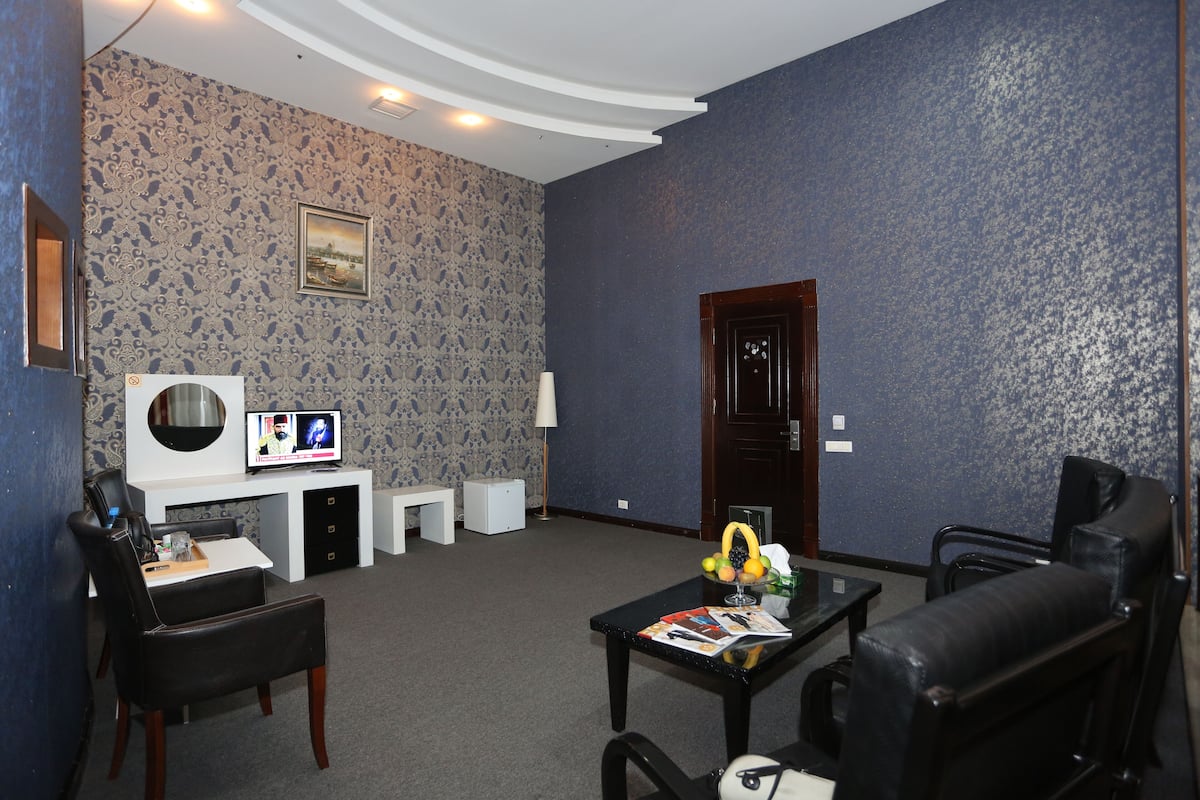 A living room with a television, a small table with magazines, a fruit bowl, and two chairs.