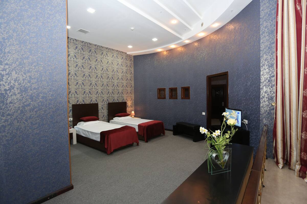 A hotel room with two beds, a desk, and a small seating area.