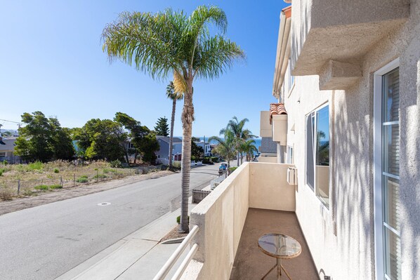 A residential street with a clear sky, a palm tree, and houses with balconies.