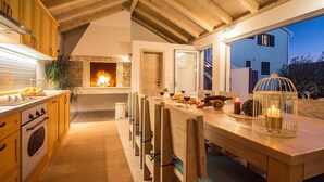 Une cuisine chaleureuse avec une cheminée, des meubles en bois et un coin repas avec une table mise pour deux personnes.