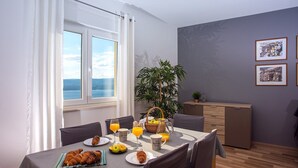 A dining area with a table set for breakfast, including croissants, fruit, and orange juice. - VILLA MASLINA, with private 32m2Pool, panoramic views on 100km coastline, 12 pax (Lokva Rogoznica)