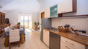 A modern kitchen with a dining area, wooden cabinets, a built-in oven, and a view to the outside. - VILLA MASLINA, with private 32m2Pool, panoramic views on 100km coastline, 12 pax (Lokva Rogoznica)