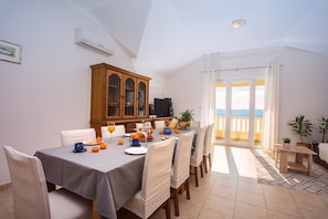 A dining area with a table set for breakfast, a wooden cabinet, and a view of the outdoors. - VILLA MASLINA, with private 32m2Pool, panoramic views on 100km coastline, 12 pax (Lokva Rogoznica)