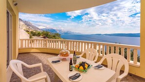 A balcony with a table set for two, overlooking a scenic view of a body of water and mountains. - VILLA MASLINA, with private 32m2Pool, panoramic views on 100km coastline, 12 pax (Lokva Rogoznica)