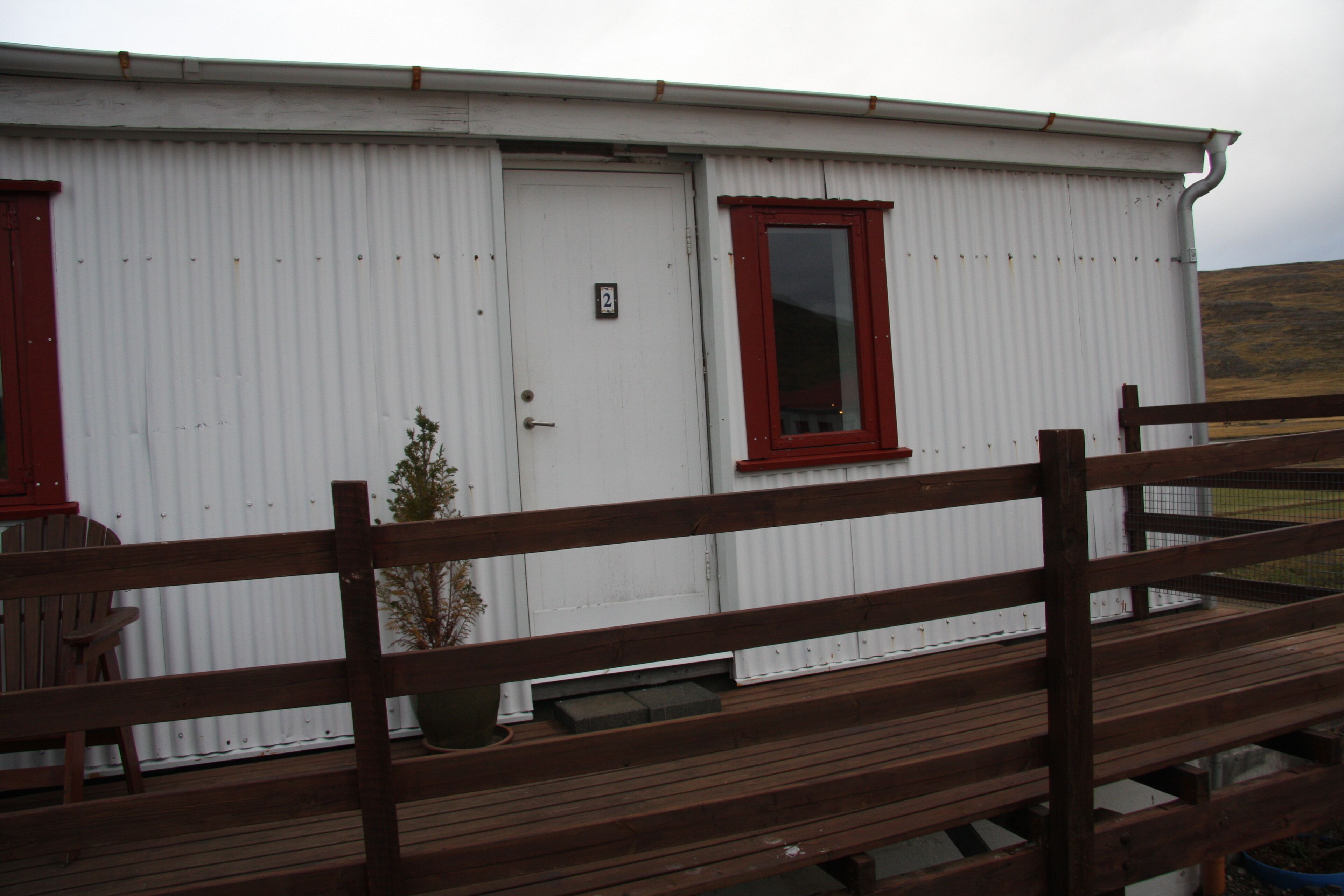 A white building with a red-framed window and a door marked with the number 2.