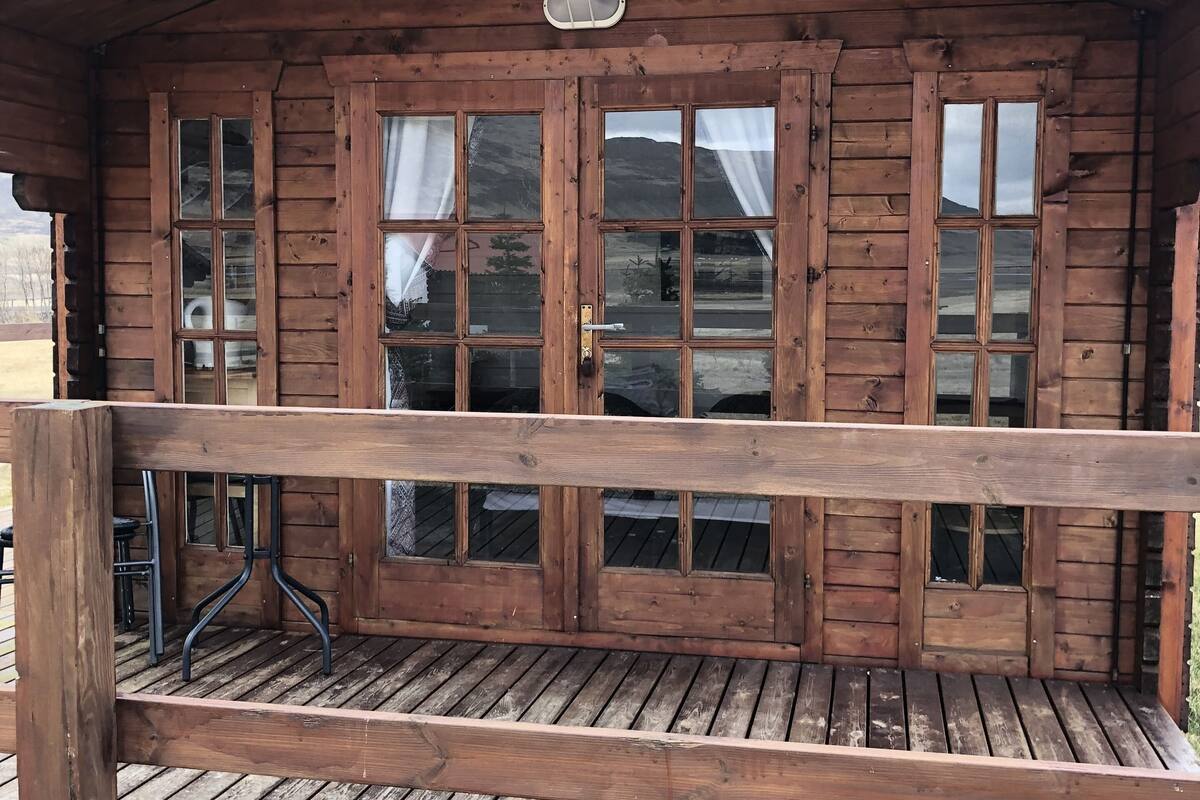 Uma cabana de madeira com varanda e uma mesa.