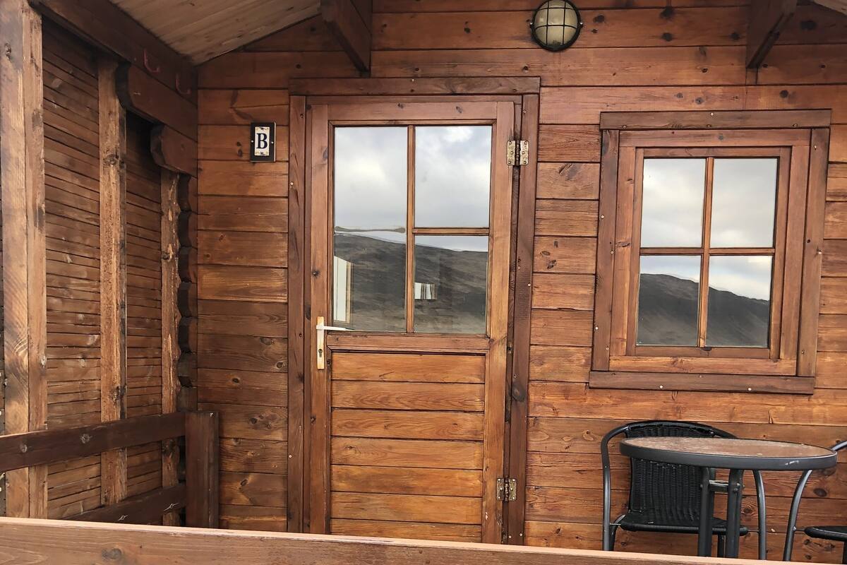 Uma cabana de madeira com varanda, mesa e cadeiras.