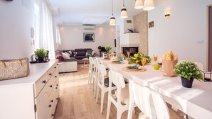 Une cuisine moderne avec un coin repas, des meubles blancs et des luminaires suspendus.