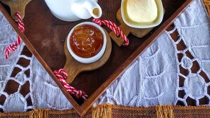 Ein Tablett mit einem Teekännchen, Orangensaftgläsern, Toast, Butter und Marmelade.