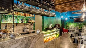 A bar area with shelves of bottles, a coffee machine, and a display of fruits. - Residenza Argileto Giallo (Rome)