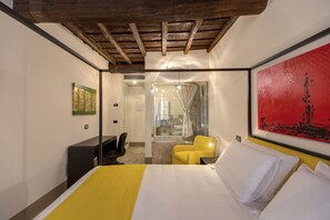 A hotel room with a bed, a desk, a chair, and a bathroom visible through a glass partition. - Residenza Argileto Giallo (Rome)