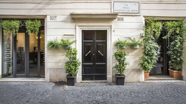A building with a black double door, potted plants, and a sign indicating 'Via R.1 Madonna dei Monti'. -  Residenze Argileto (Rome)