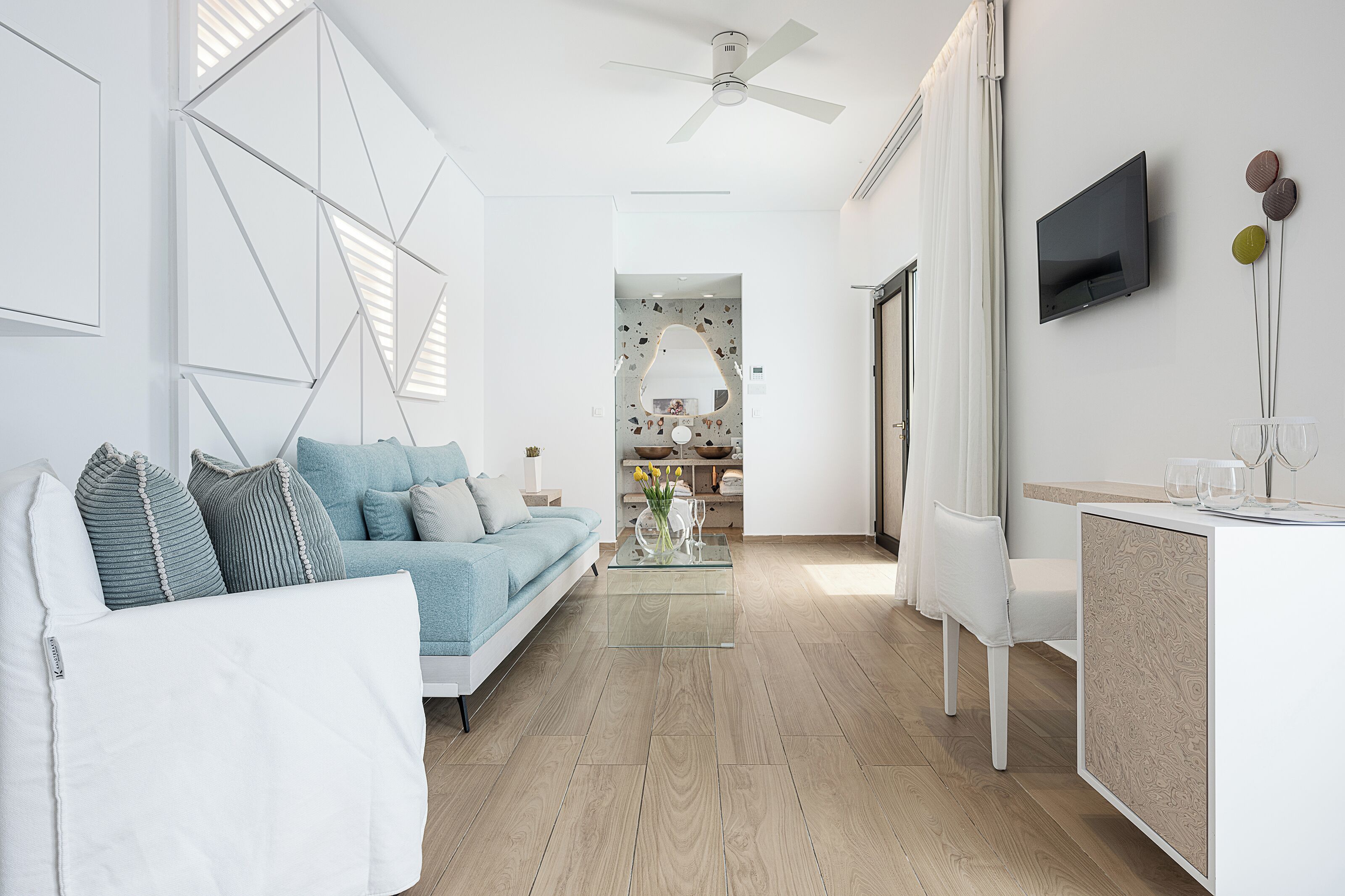 Una sala de estar moderna con un sofá, una mesa de centro y un televisor montado en la pared.
