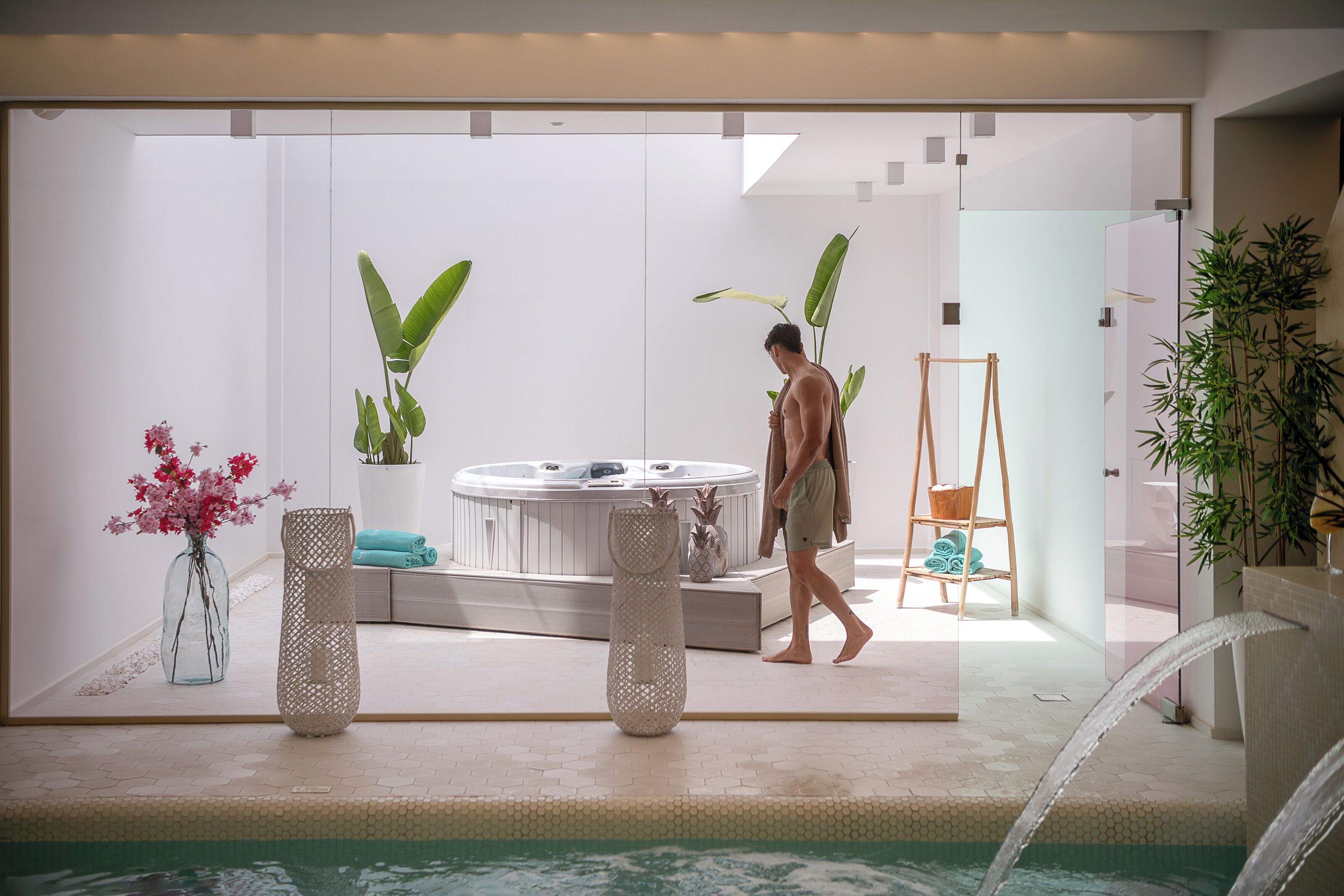 Un área de piscina interior moderna con jacuzzi, sillones reclinables y plantas en macetas.