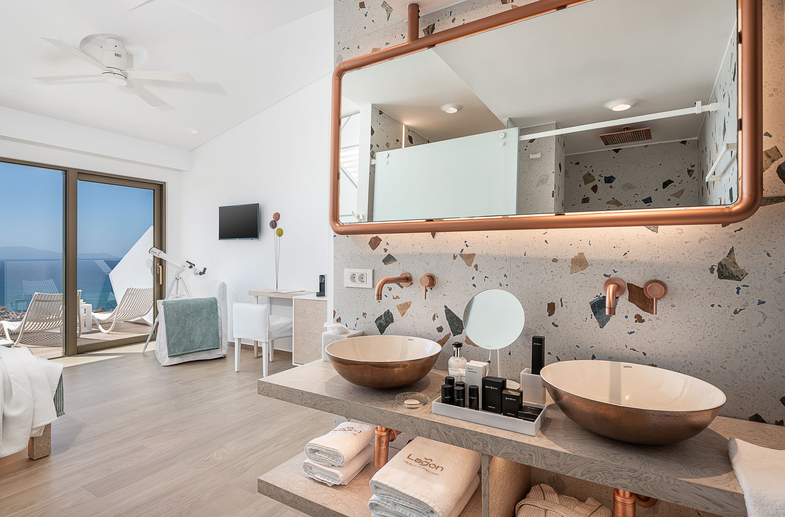 A modern bathroom with a large mirror, two vessel sinks, and a view of the ocean.