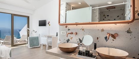 A modern bathroom with a large mirror, two vessel sinks, and a view of the ocean.