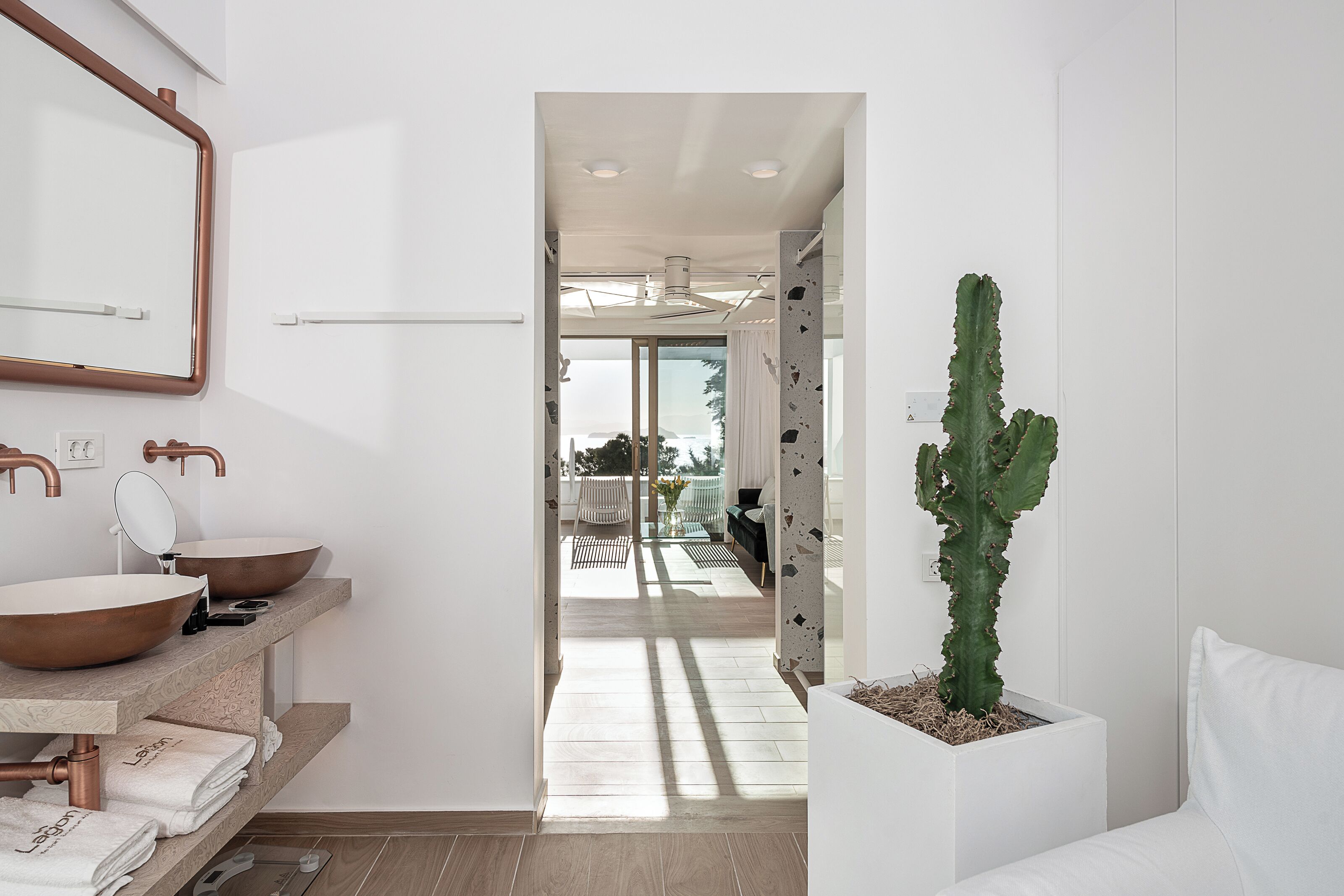 Un baño moderno con un espejo grande, dos lavamanos y una planta de cactus.