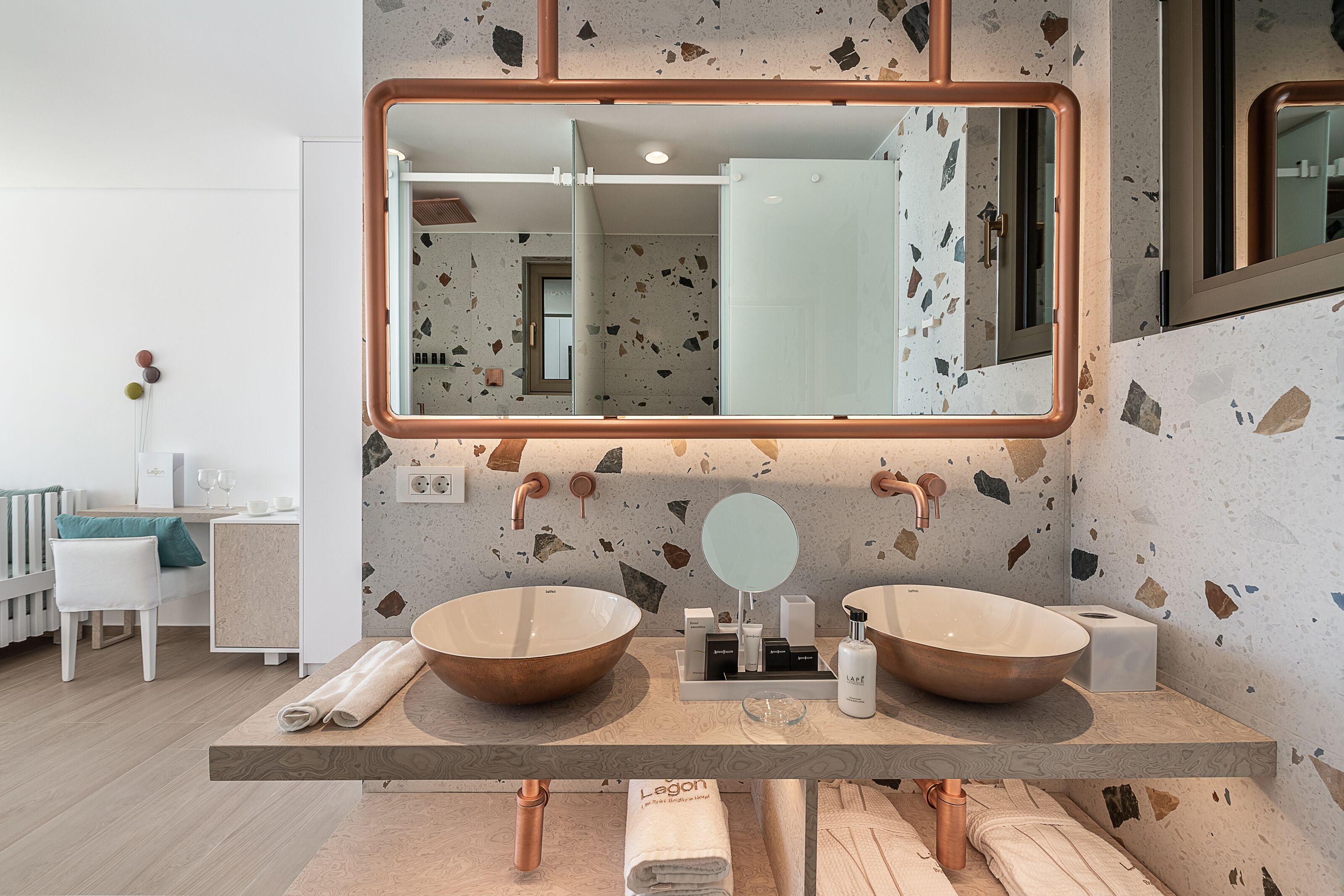 Un baño con dos lavamanos grandes de cobre, un espejo amplio y una encimera con artículos de aseo.