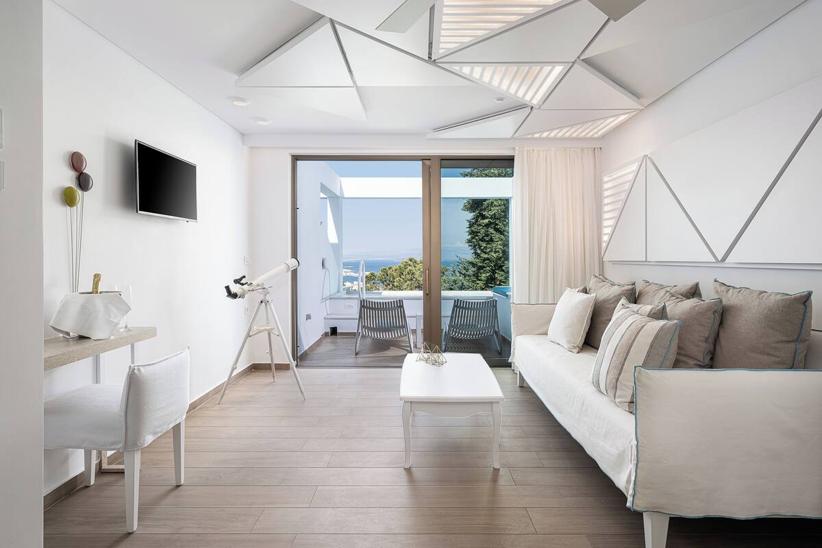 Una sala de estar moderna con un sofá blanco, una mesa de centro y un telescopio sobre un trípode.