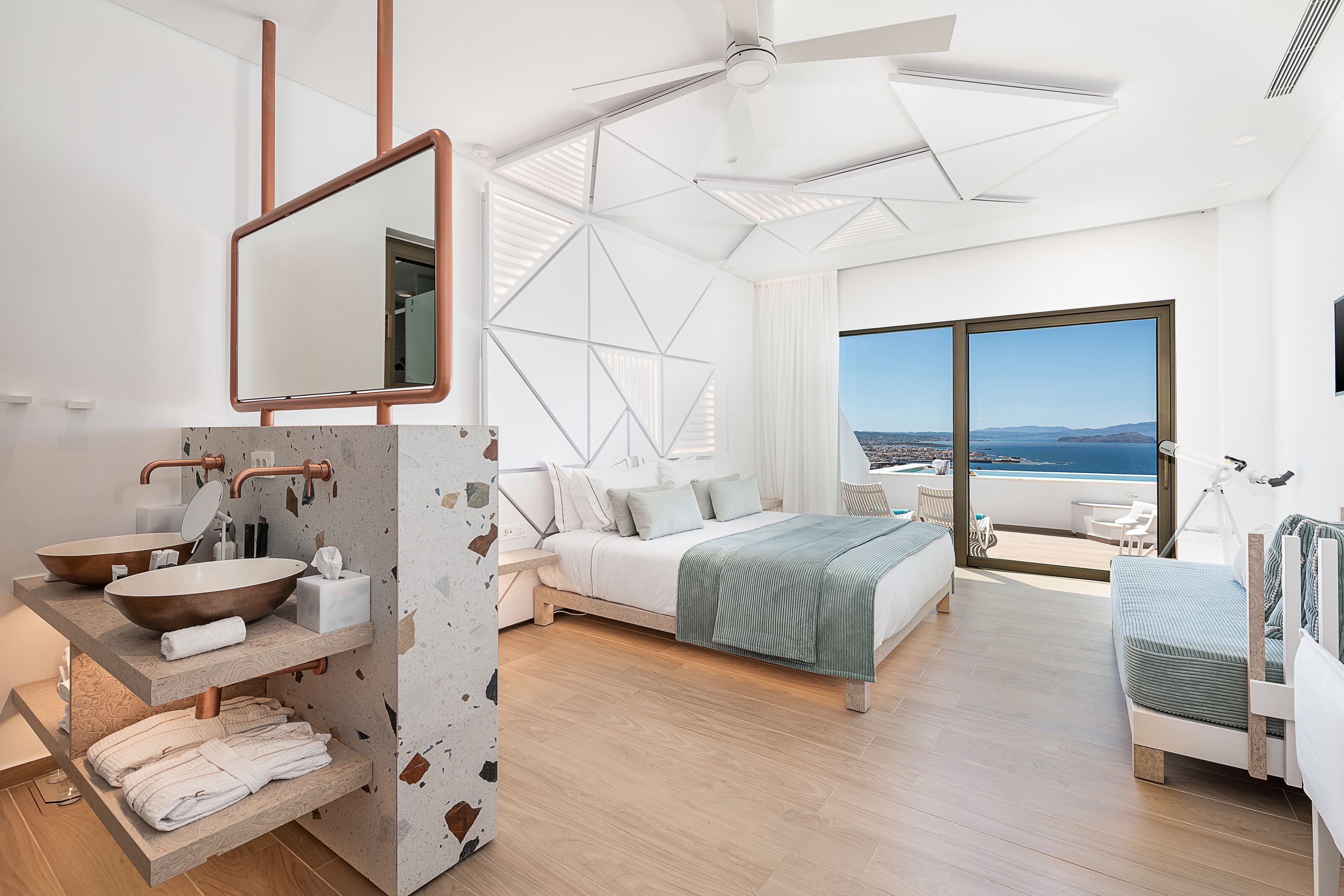 Ein modernes Schlafzimmer mit einem großen Bett, ein Badezimmer mit einem großen Waschbecken und Spiegel sowie ein Balkon mit Aussicht.