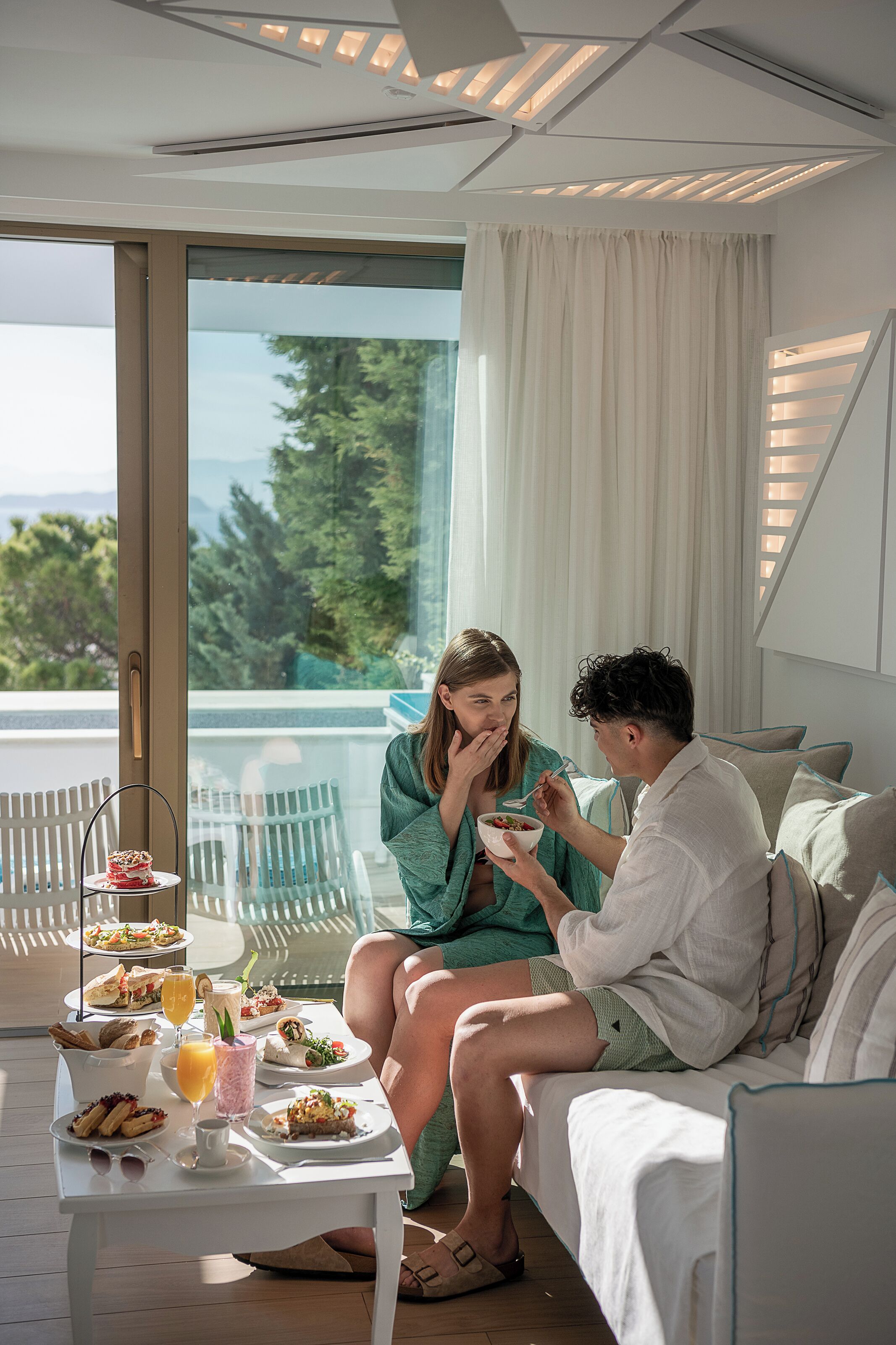 A couple dining on a balcony with a table set with breakfast items and a view of the outdoors.