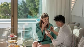 A couple dining on a balcony with a table set with breakfast items and a view of the outdoors.
