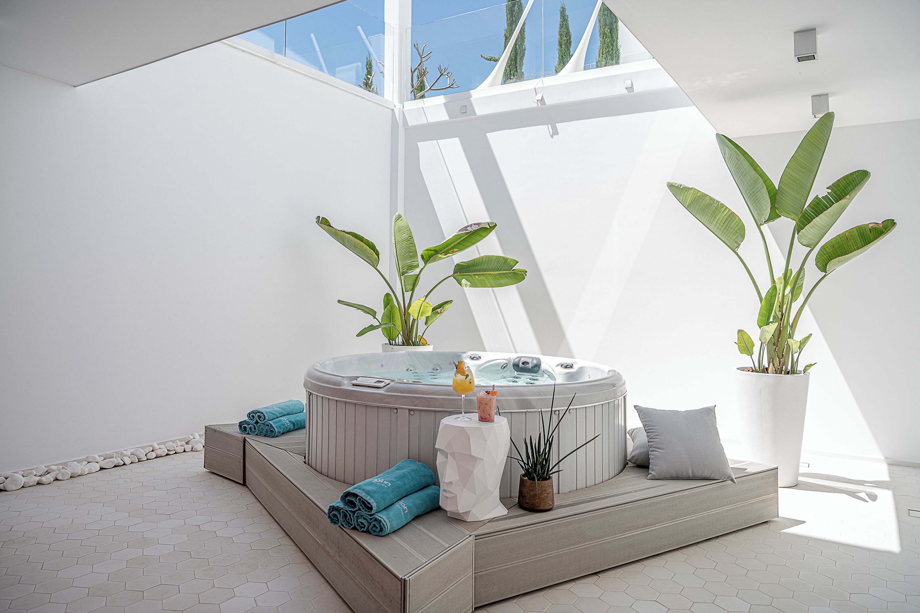 Un área de spa moderna con un jacuzzi, plantas en macetas y toallas ordenadas.