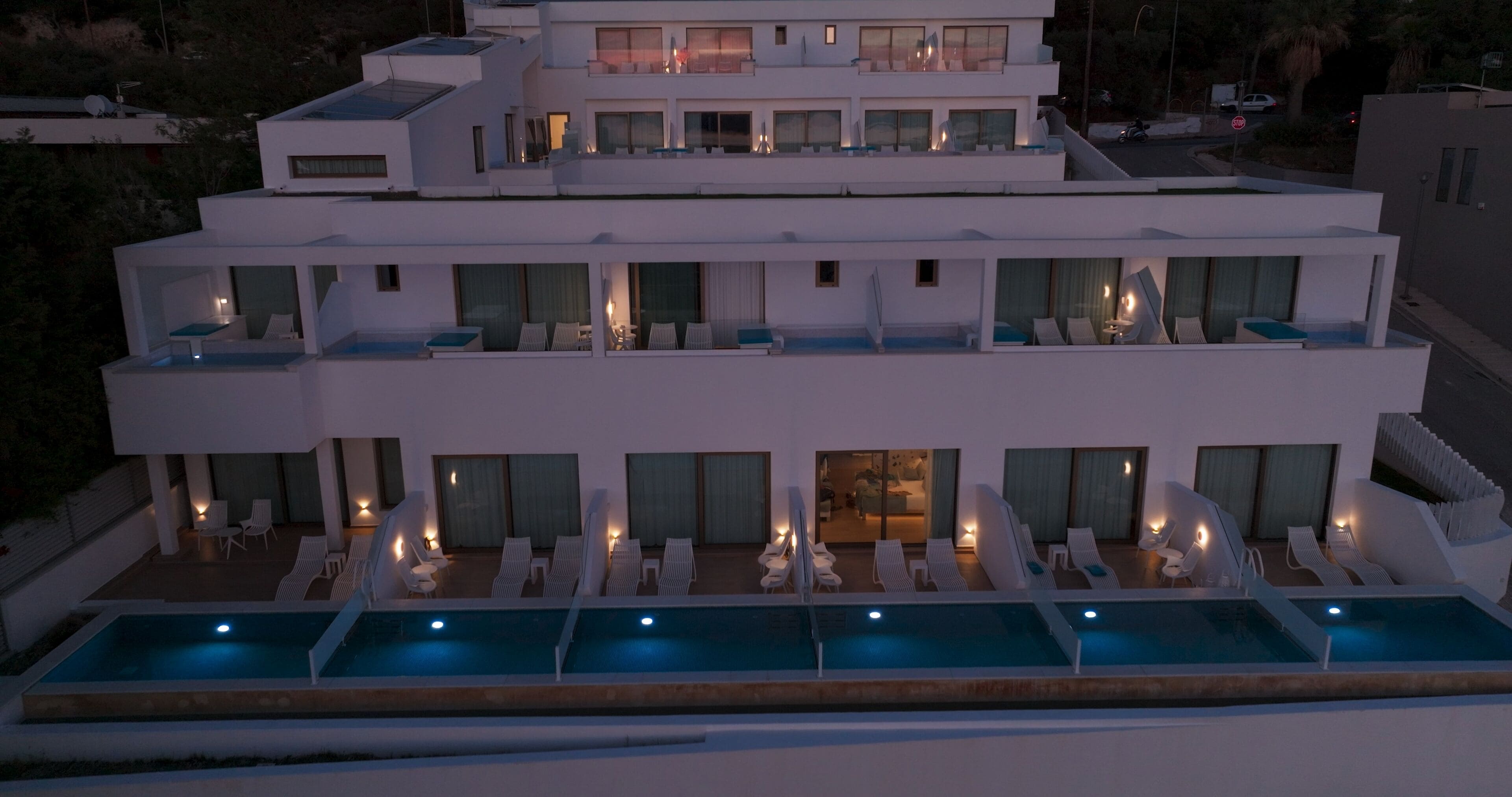 Un hôtel moderne à plusieurs étages, doté d’une piscine sur le toit, de nombreux balcons et d’un intérieur bien éclairé.