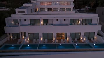 Un hôtel moderne à plusieurs étages, doté d’une piscine sur le toit, de nombreux balcons et d’un intérieur bien éclairé.