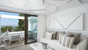 A modern living room with a white sofa, a glass coffee table, and a view of the outdoors.