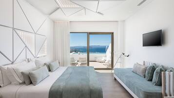 A modern hotel room with a large bed, a sofa, and a balcony with a view of the sea.