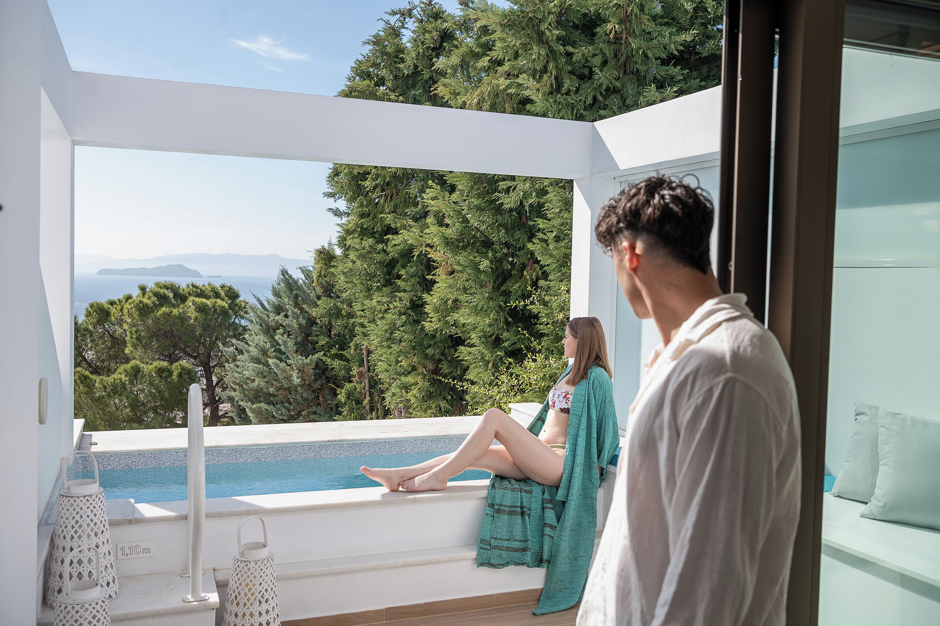 A modern outdoor seating area with a pool, overlooking a mountainous landscape.