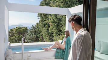 A modern outdoor seating area with a pool, overlooking a mountainous landscape.