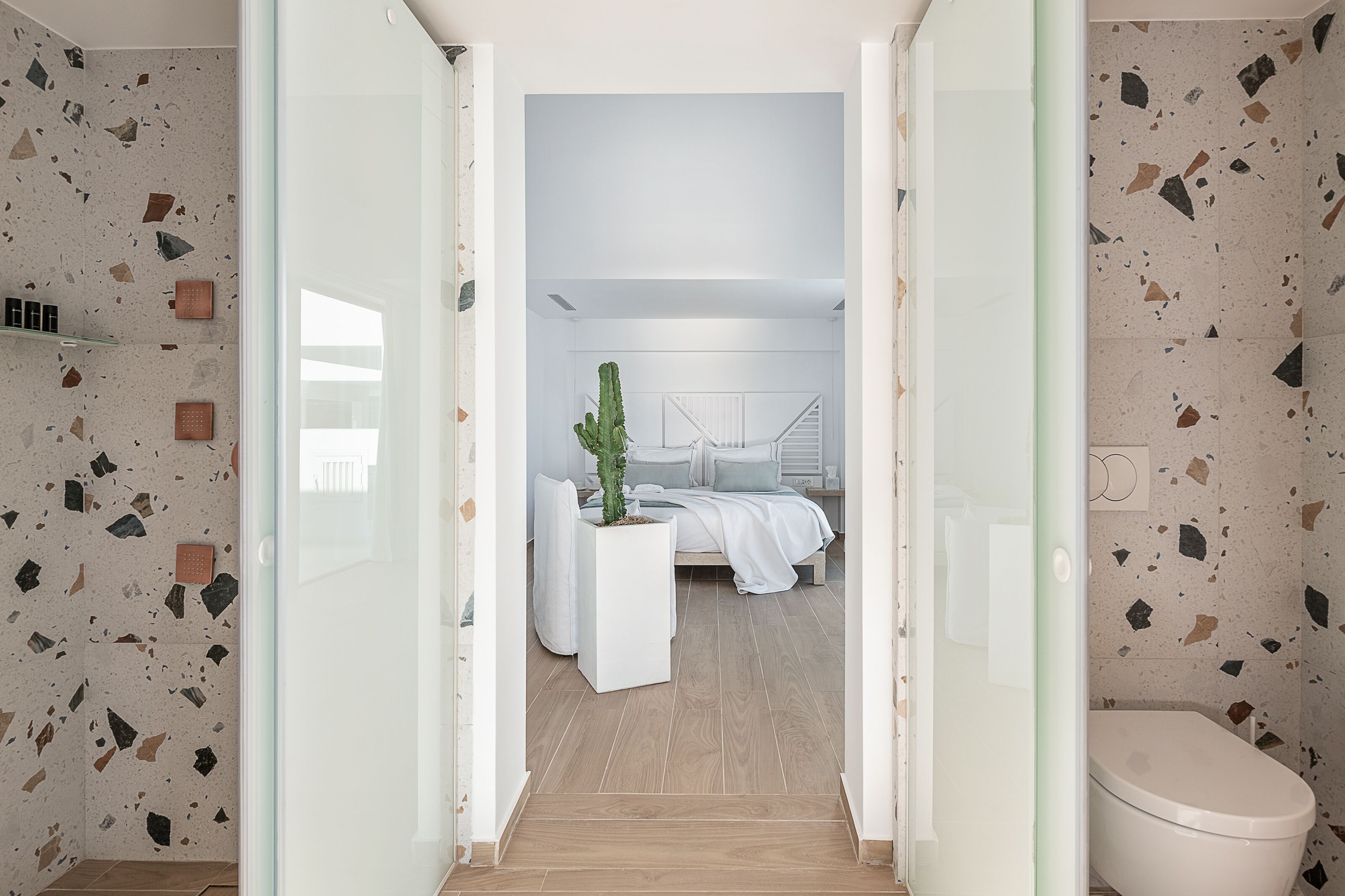Ein modernes Schlafzimmer mit einem Bett, Nachttischen und einer Sukkulente.