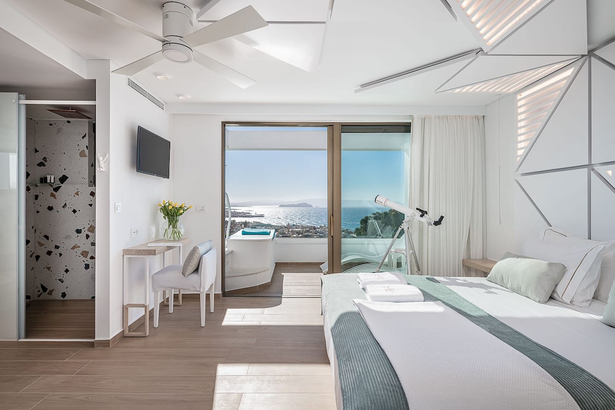 Habitación de hotel moderna con una cama grande, un escritorio y vistas al mar.