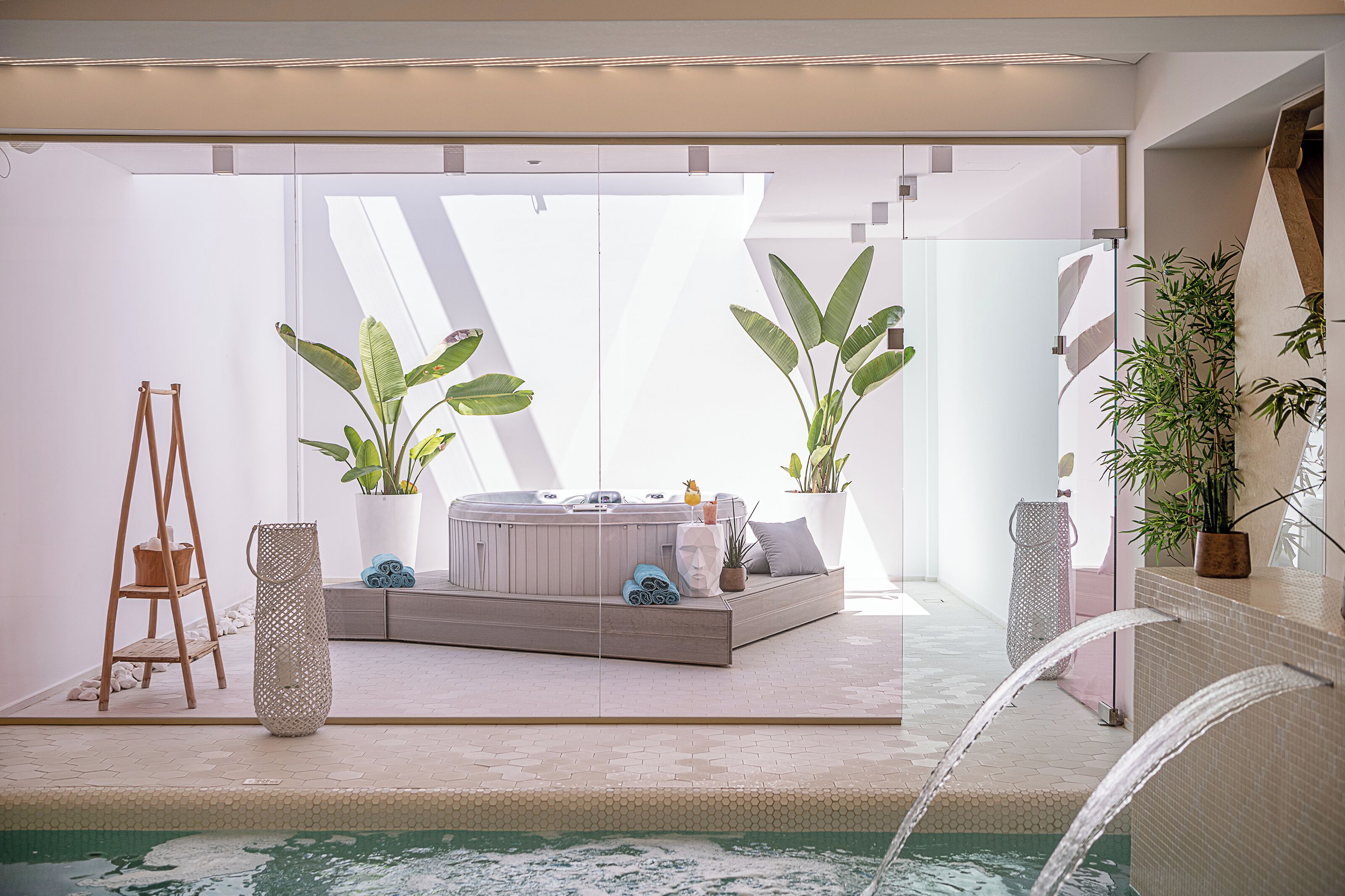 Un moderno espacio de spa con hidromasaje, asientos y plantas en macetas.