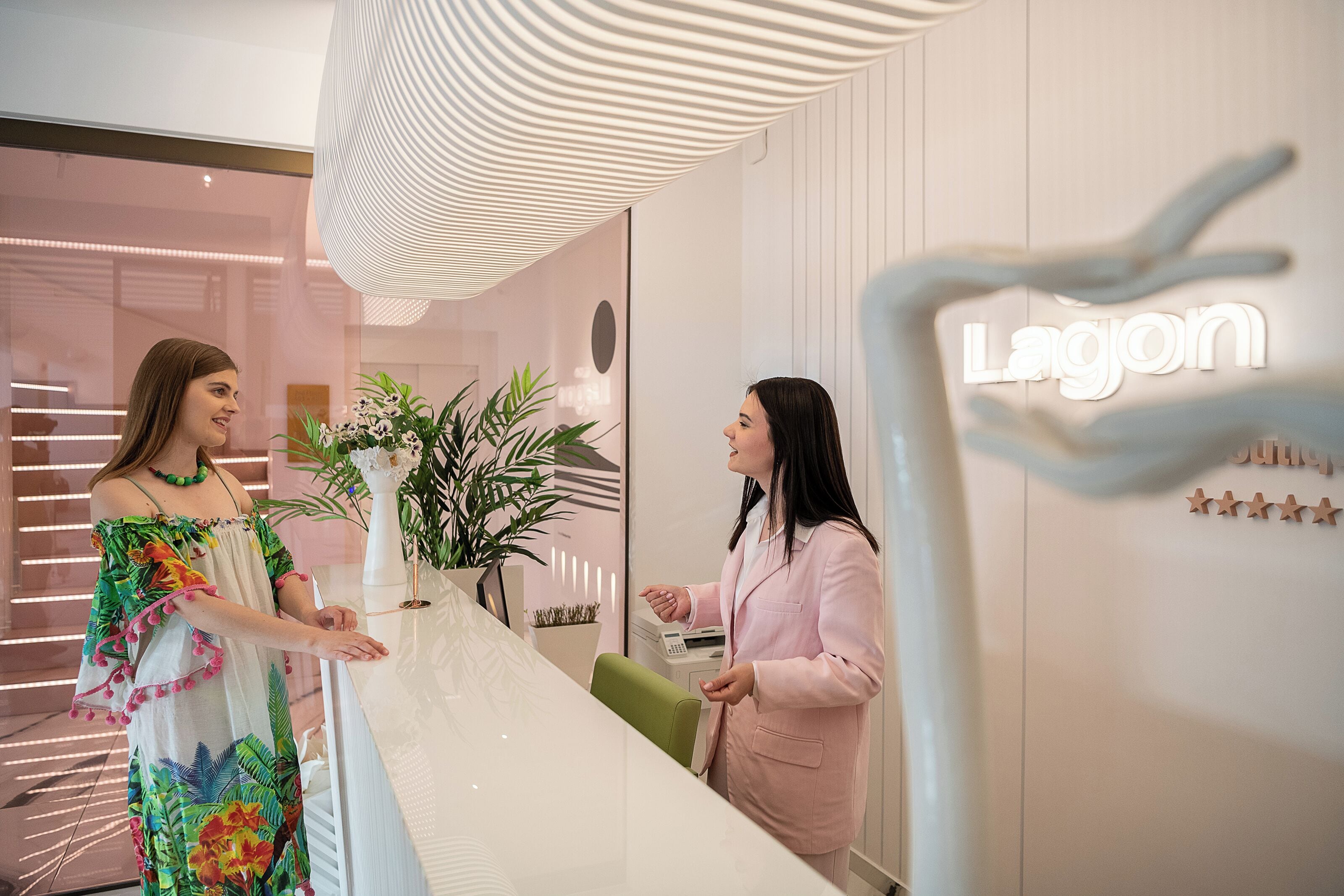 Et moderne receptionsområde med en receptionsdisk, en potteplante og et skilt på væggen med teksten "Lagoon".