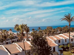 A coastal resort with multiple buildings, palm trees, and a view of the ocean.