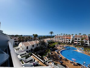 A resort with a large pool, multiple buildings, and a clear view of the sea.