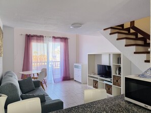 A living room with a sofa, TV, and a staircase. - Golden View Holiday Home (Playa de las Américas)