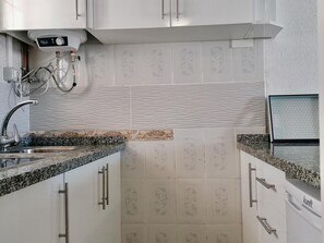 A kitchen with white cabinets, a granite countertop, and a built-in dishwasher.