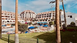 Ein Resort mit mehrstöckigen Gebäuden, einem Poolbereich mit Liegestühlen und Palmen.