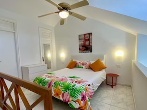 A bedroom with a bed, a ceiling fan, a painting, and a nightstand. - Golden View Holiday Home (Playa de las Américas)