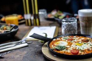 Una mesa de comedor con un plato en sartén, cubiertos y una carta.