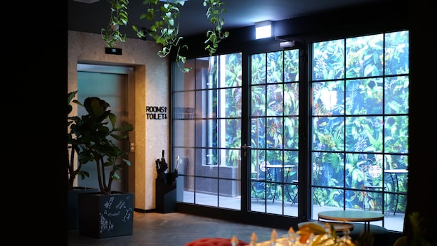 A hotel lobby with a large window, a sign for the room service toilet, and a seating area with a table and chairs.