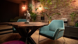 A cozy room with a rustic brick wall, a wooden table, and a plush blue armchair.