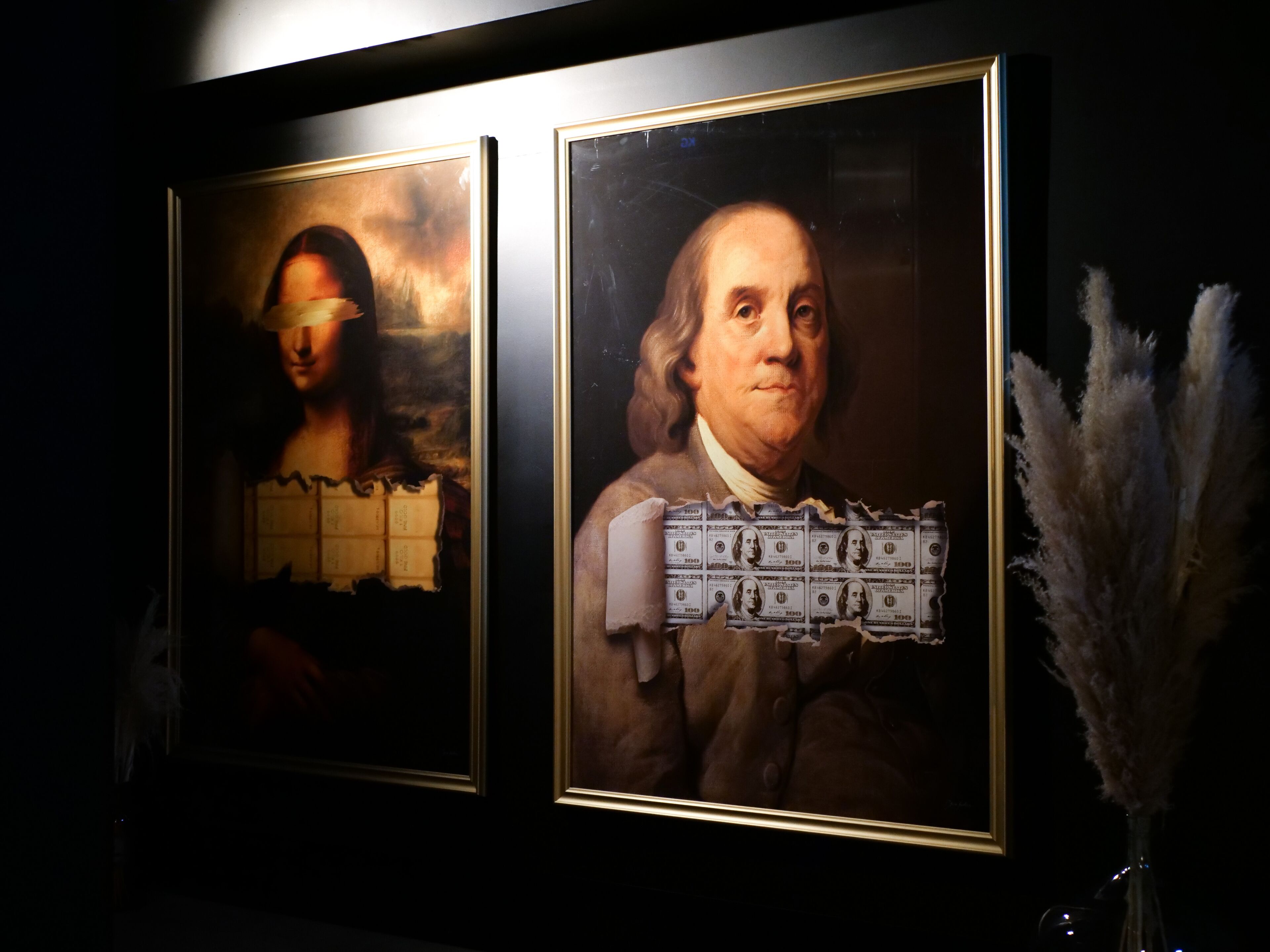 Two framed artworks on a wall, one depicting a classical painting with a figure and the other a portrait of a historical figure with currency notes superimposed.