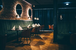 Un restaurante con paredes de ladrillo, asientos tapizados en verde y suelo de madera.