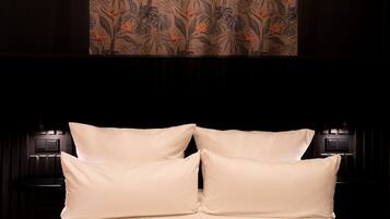Una cama con cuatro almohadas y un cabecero con apliques de pared.