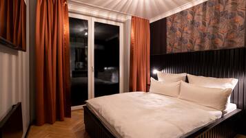 A bedroom with a bed, curtains, a patterned wall, and a ceiling light.